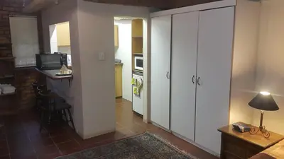 a kitchen with white cabinets and a table in a room at Albatross B&B in Benoni