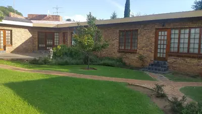 a brick house with a tree in the yard at Albatross B&B in Benoni