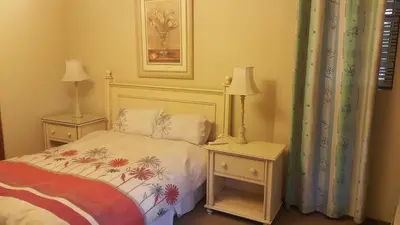 a bedroom with a bed and two night tables with lamps at Albatross B&B in Benoni