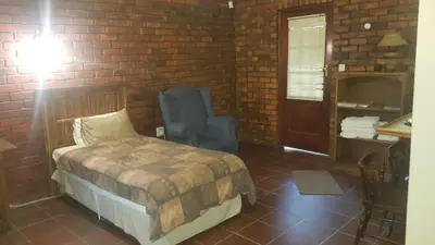 a bedroom with a bed and a brick wall at Albatross B&B in Benoni