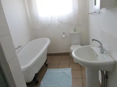 a bathroom with a tub and a toilet and a sink at Absolute Leisure Cottages in Machadodorp