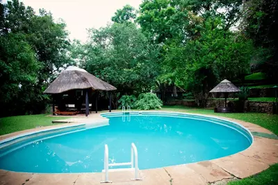a swimming pool with a chair and a gazebo at Lepêllê Lodge in Burgersfort