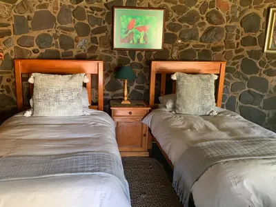 two beds in a room with stone walls at Lepêllê Lodge in Burgersfort