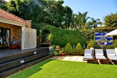 a backyard with chairs and a deck with a lawn at Annie's Boutique Guesthouse and Garden Spa in Hartbeespoort