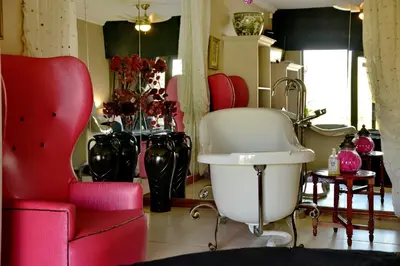 a salon with red chairs and a white chair at Annie's Boutique Guesthouse and Garden Spa in Hartbeespoort