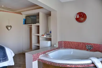 a bath tub in a bathroom with red tile at Annie's Boutique Guesthouse and Garden Spa in Hartbeespoort
