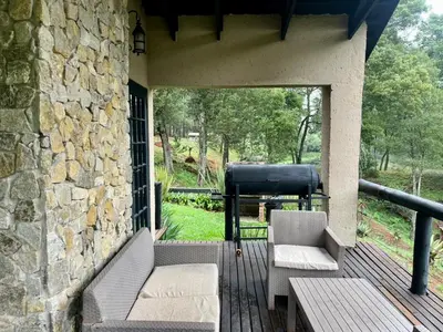 a porch with two chairs and a stone wall at Silver Mist Resort, Haenertsburg in Haenertsburg