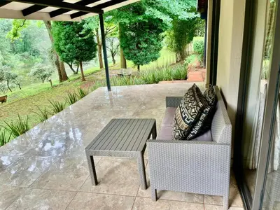 a patio with a table and a chair and an umbrella at Silver Mist Resort, Haenertsburg in Haenertsburg