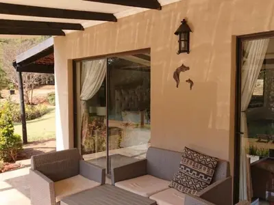a house with a porch with a couch and birds on the wall at Silver Mist Resort, Haenertsburg in Haenertsburg