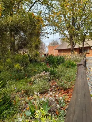 a wooden fence in a garden with a house at Munati B&B in Musina