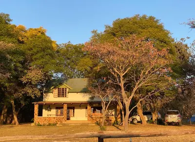 a white house with a tree in front of it at Waterberg Cottages, Private Game Reserve in Vaalwater