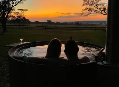 two people sitting in a hot tub watching the sunset at Waterberg Cottages, Private Game Reserve in Vaalwater