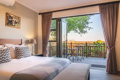 a bedroom with a bed and a balcony with a large window at Elephant Point in Skukuza