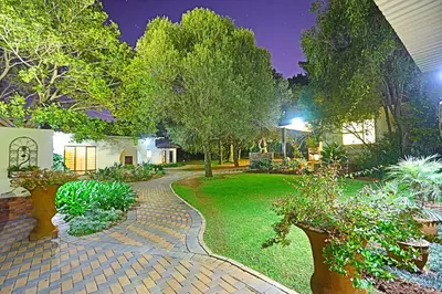 a garden at night with a brick walkway at Andante Lodge in Pretoria