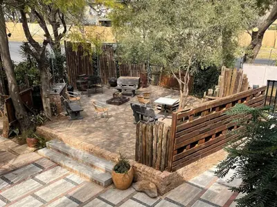 a backyard with a wooden fence and a grill at Africa Footprints Lodge Kempton Park in Kempton Park