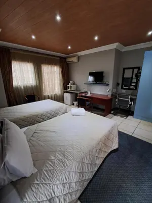 a hotel room with two beds and a piano at Constantia Manor Guest House in Pretoria