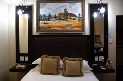 a bedroom with a bed with two pillows and a painting at Constantia Manor Guest House in Pretoria