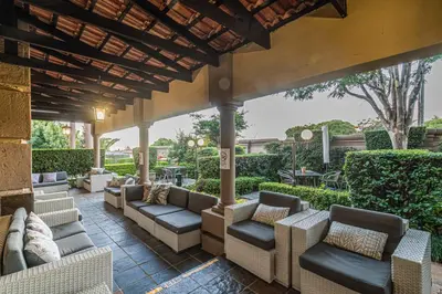 an outdoor patio with couches and chairs under a pergola at Constantia Manor Guest House in Pretoria