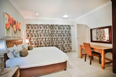 a bedroom with a bed and a table and a desk at Accommodation at Vans No Loadshedding in Centurion