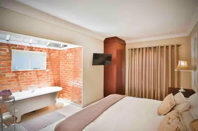 a bedroom with a bed and a bath tub next to a brick wall at Accommodation at Vans No Loadshedding in Centurion