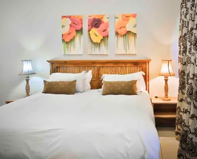 a bedroom with a white bed with three paintings on the wall at Accommodation at Vans No Loadshedding in Centurion