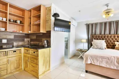 a bedroom with a bed and a sink and a kitchen at Accommodation at Vans No Loadshedding in Centurion