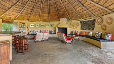 a room with chairs and a fireplace in a house at Umlani Bushcamp in Timbavati Game Reserve