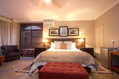 a bedroom with a large bed with a red ottoman at Leopardsong Manor in Centurion