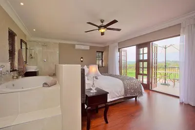 a bedroom with a bed and a bath tub and a ceiling fan at Leopardsong Manor in Centurion
