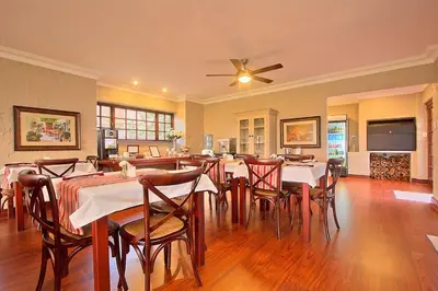 a dining room with tables and chairs and a ceiling fan at Leopardsong Manor in Centurion