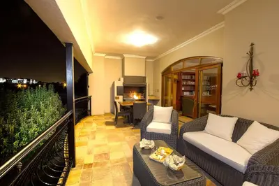 a living room with couches and a balcony with a table at Leopardsong Manor in Centurion