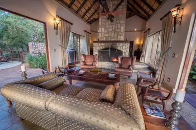 a living room with a couch and a fireplace at Shumbalala Game Lodge in Thornybush Game Reserve