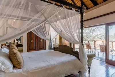 a bedroom with a canopy bed and a balcony at Shumbalala Game Lodge in Thornybush Game Reserve