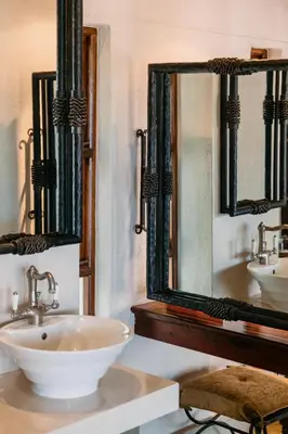a bathroom with a sink and two mirrors at Shumbalala Game Lodge in Thornybush Game Reserve
