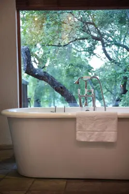 a bath tub with a sink and a window at Shumbalala Game Lodge in Thornybush Game Reserve