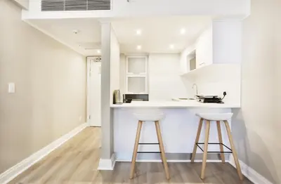 a kitchen with white cabinets and two stools at RH Hotel & Apartments - Pretoria in Pretoria