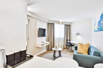 a hotel room with a blue couch and a table at RH Hotel & Apartments - Pretoria in Pretoria