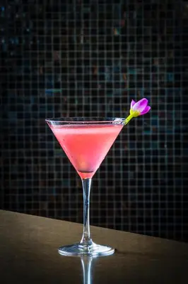 a pink drink in a glass with a flower in it at RH Hotel & Apartments - Pretoria in Pretoria