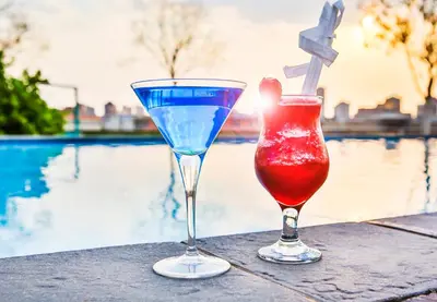 two cocktails sitting on a table next to a pool at RH Hotel & Apartments - Pretoria in Pretoria