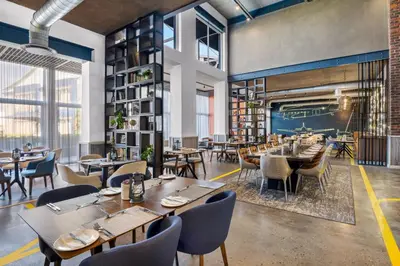 a restaurant with tables and chairs and a fireplace at Protea Hotel by Marriott O R Tambo Airport in Kempton Park