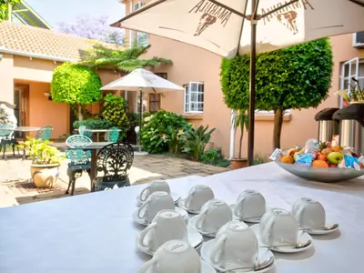 a table with plates and cups and a bowl of fruit at The Elegant Lodge Menlo Park in Pretoria