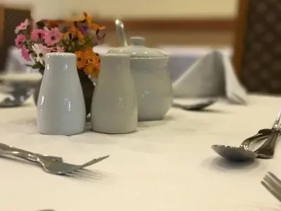 a table with two white containers and flowers on it at The Elegant Lodge Menlo Park in Pretoria