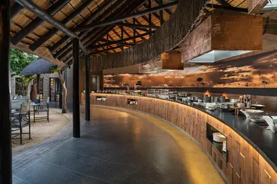 a restaurant with a bar with a sunset mural on the wall at Kruger Gate Hotel in Skukuza