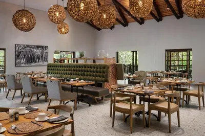 a restaurant with tables and chairs and chandeliers at Kruger Gate Hotel in Skukuza