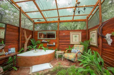 a large bathroom with a tub and a chair at Wielewaal Bush Lodge in Marloth Park