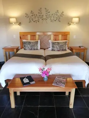 a bedroom with a large bed with a wooden table at Idle & Wild Chalet in Hazyview