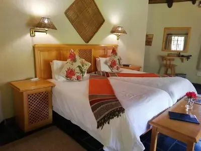 a bedroom with a bed with white sheets and pillows at Idle & Wild Chalet in Hazyview