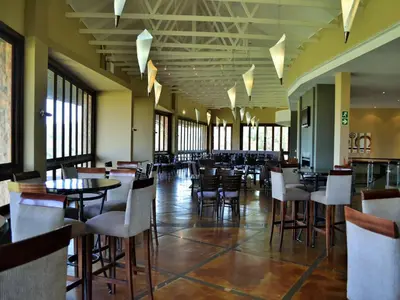 a dining room with tables and chairs and windows at Elements Private Golf Reserve in Bela-Bela