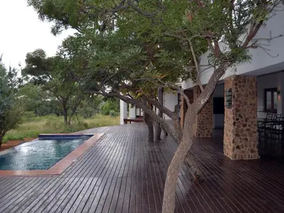 a wooden deck with a tree next to a house at Elements Private Golf Reserve in Bela-Bela