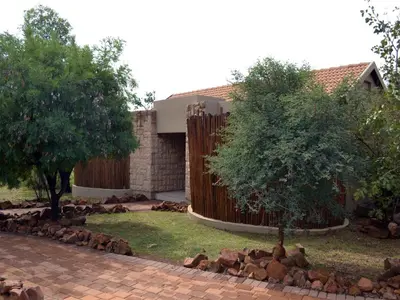 a house with a fence and a tree in the yard at Elements Private Golf Reserve in Bela-Bela